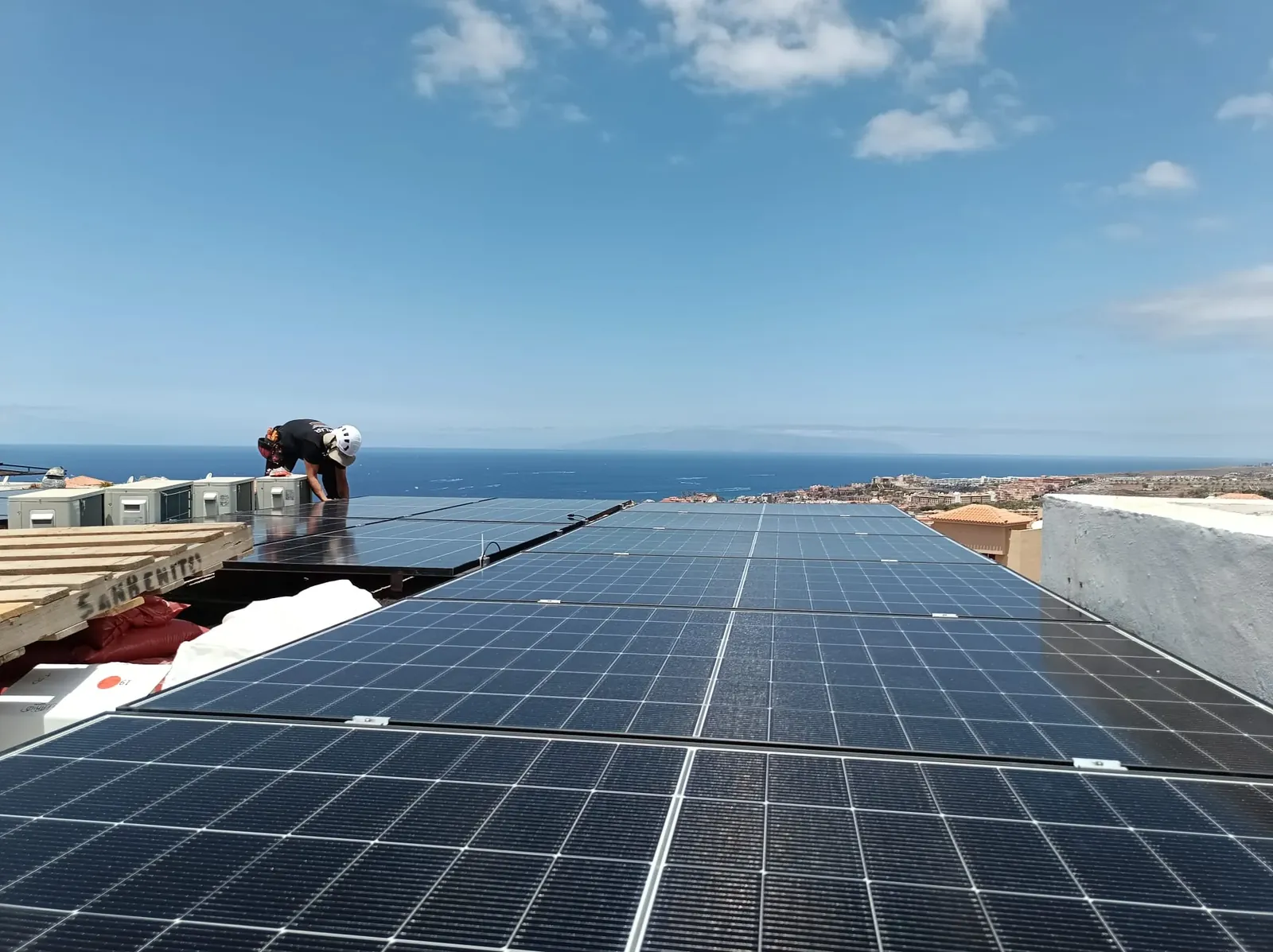 Campo de paneles solares instalado en una cubierta con vistas a la costa de Tenerife