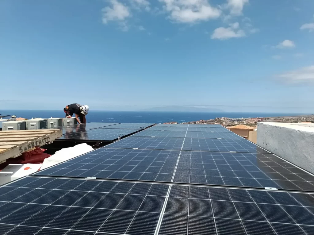 Campo de paneles solares instalado en una cubierta con vistas a la costa de Tenerife